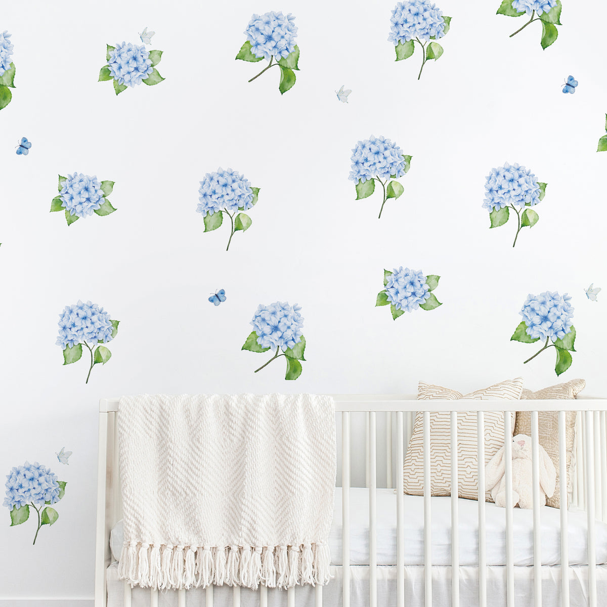 Nursery room with white crib and blue hydrangea wall decals with butterflies on a white background