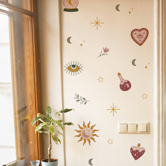 Decorative wall stickers on a light-colored wall with a plant and window in the background.