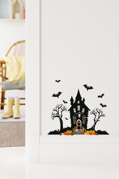 Halloween-themed wall decal of a haunted house with bats and pumpkins on a white wall.