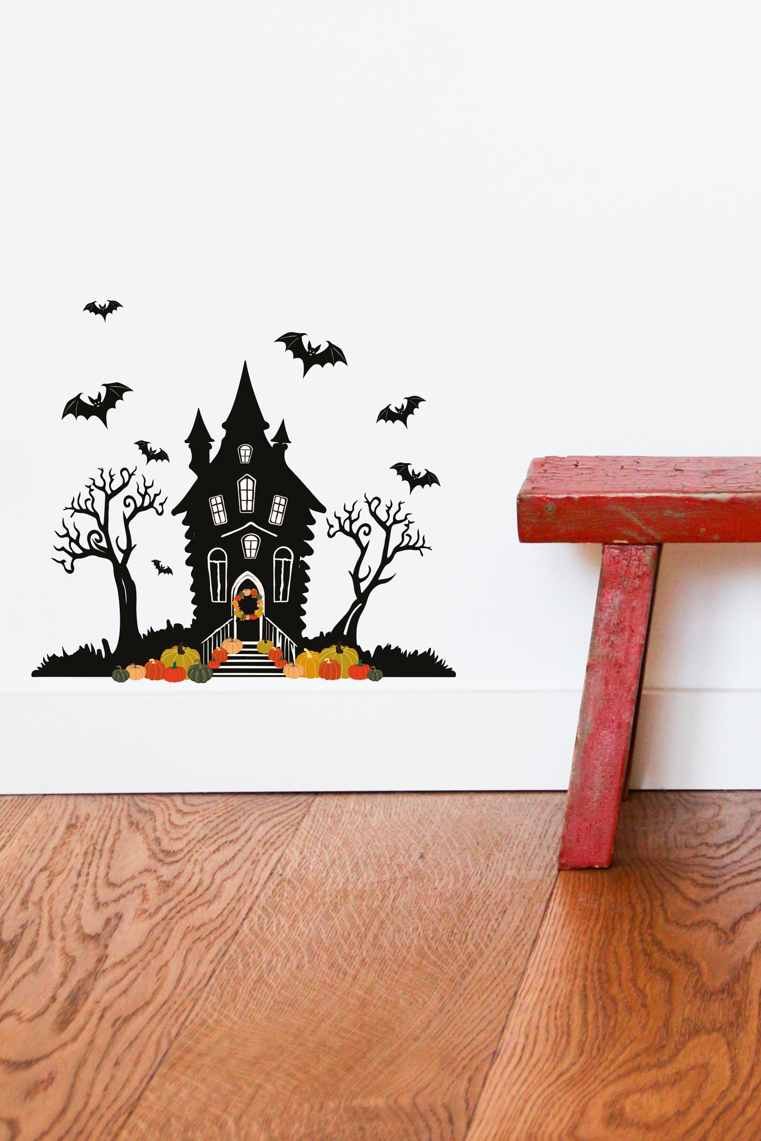 Halloween Spooky Haunted House Wall Sticker sat above white skirting board next to a red wooden stool
