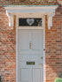 Light blue door with decorative heart above number 30 on a brick wall