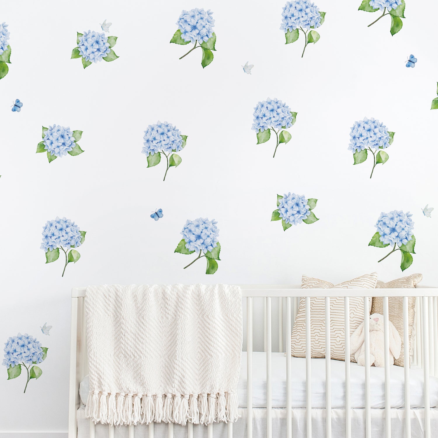 Nursery room with white crib and blue hydrangea wall decals with butterflies on a white background
