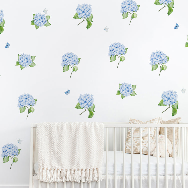 Nursery room with white crib and blue hydrangea wall decals with butterflies on a white background