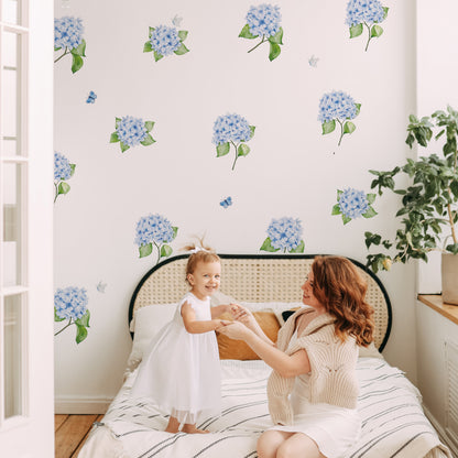 Woman and child sitting on a bed with Hydrangea Flowers and butterflies wall decals in a bedroom.