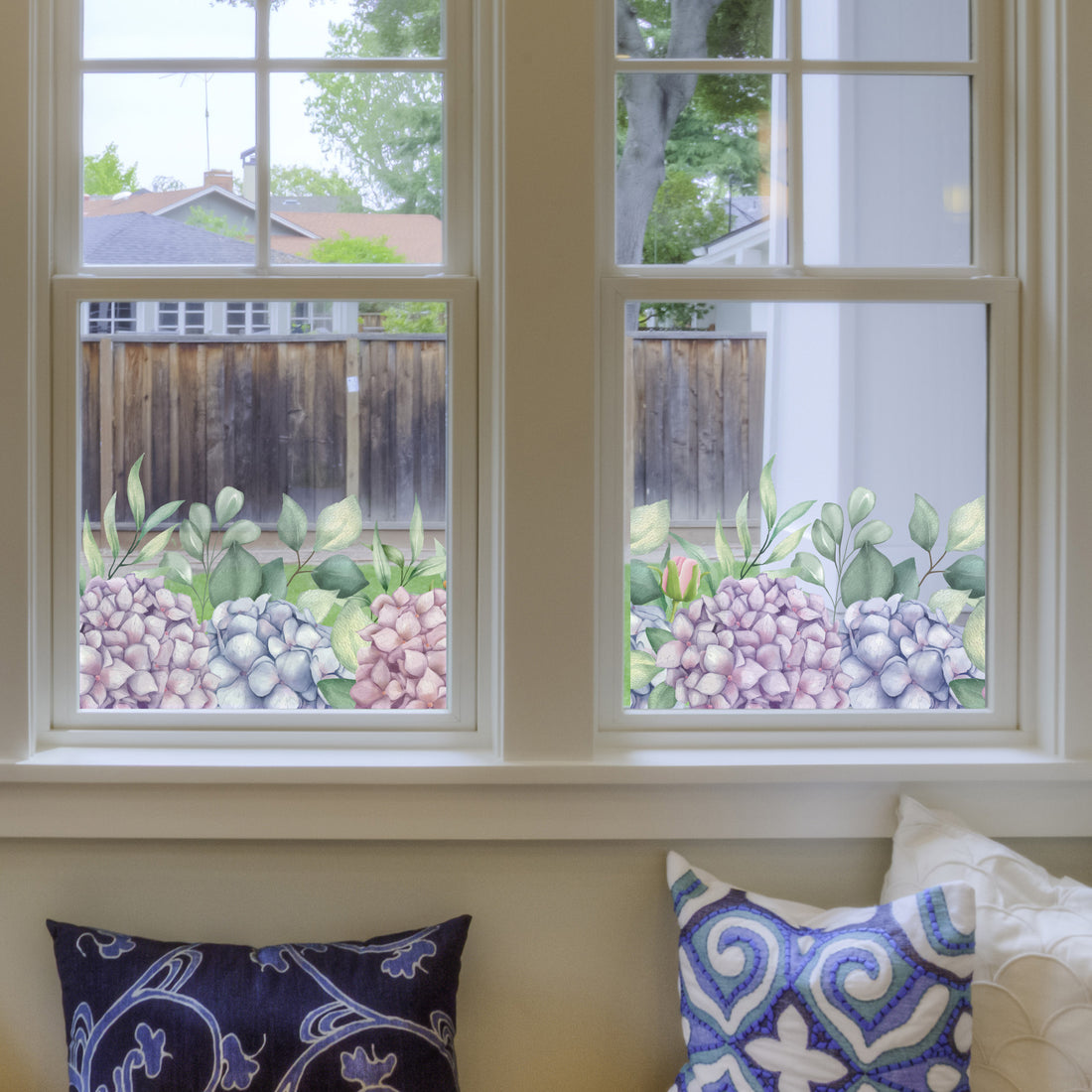 Decorative Hydrangea window Sticker on a window, with pillows on a couch below.