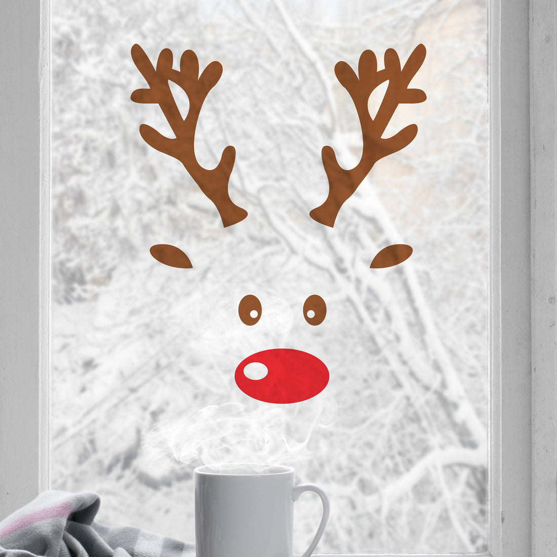 Reindeer face window decal on a frosted glass door with a white mug in the foreground.