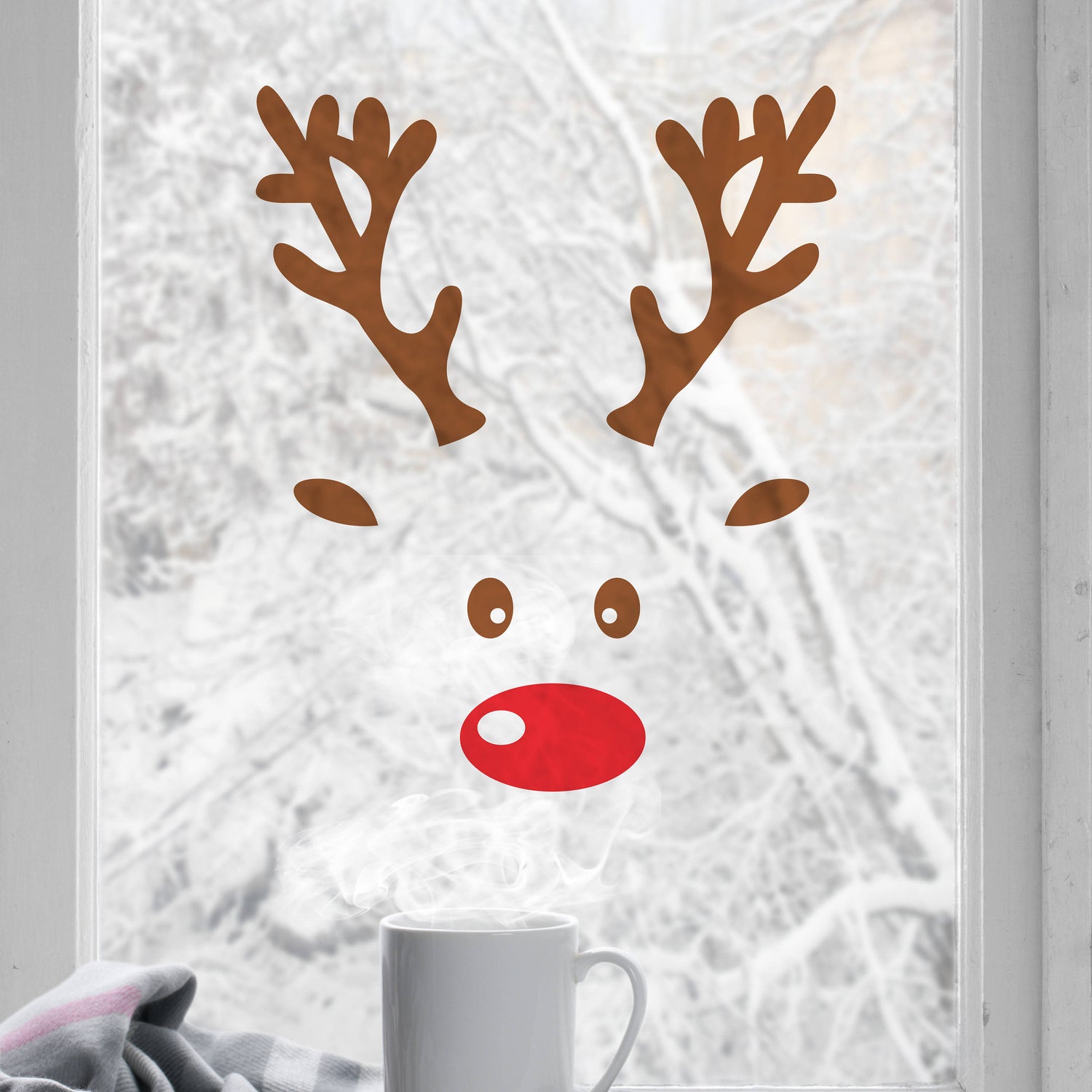 Reindeer face window decal on a frosted glass door with a white mug in the foreground.