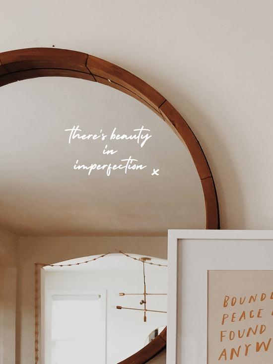Round mirror with wooden frame on a wall with text &