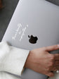 Person holding a laptop with a black decal and white text on a gray surface