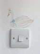 Decorative swan sticker with a crown and blue bow on a light switch.