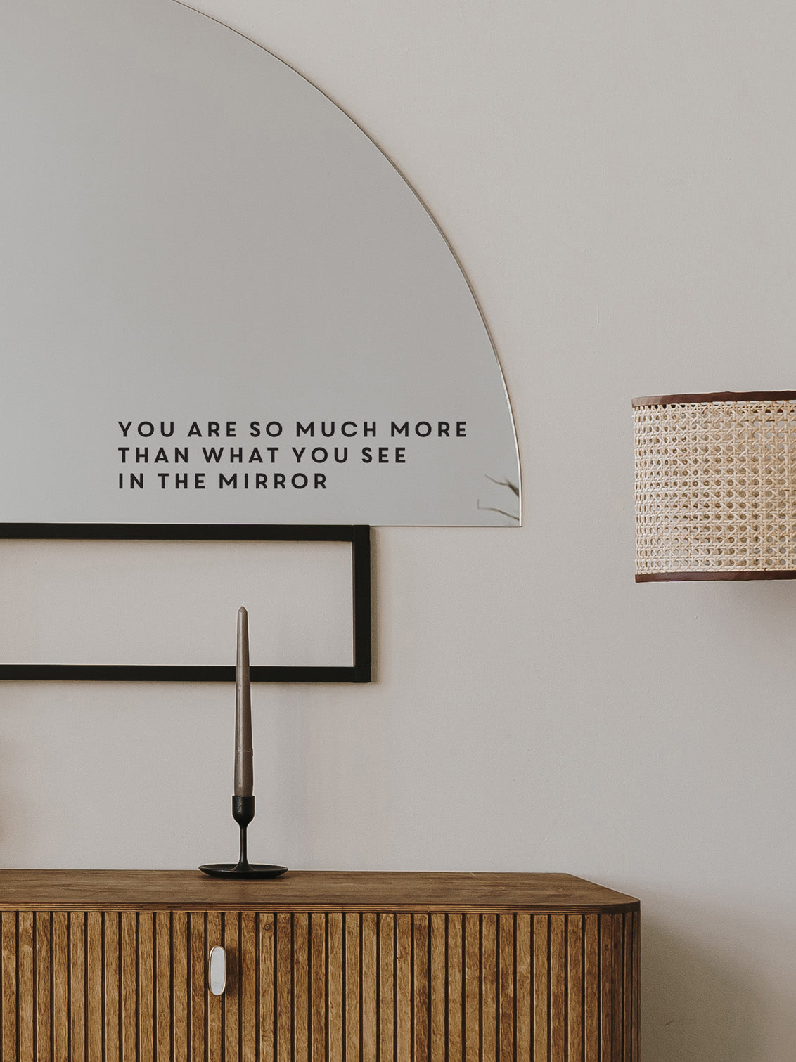 Decorative mirror with motivational quote above a wooden cabinet.