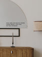 Decorative mirror with motivational quote above a wooden cabinet.