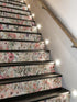 Staircase with floral patterned steps and wall lights.