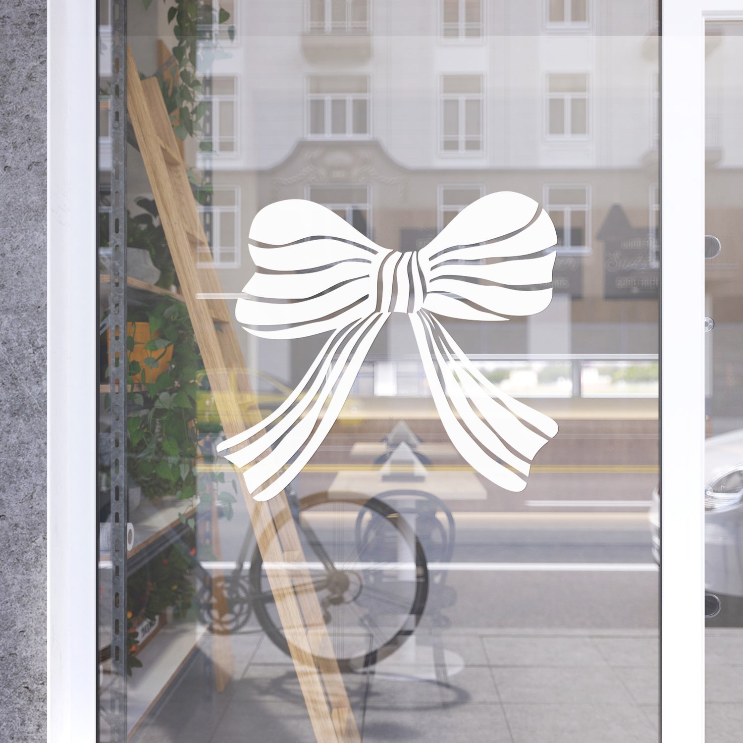 Decorative white bow design on a glass door with a blurred street scene in the background.