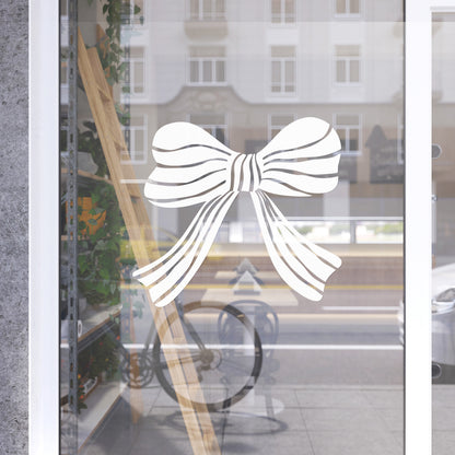 Decorative white bow design on a glass door with a blurred street scene in the background.