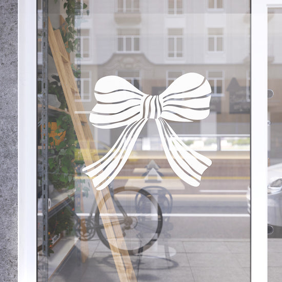 Decorative white bow design on a glass door with a blurred street scene in the background.
