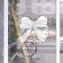 Decorative white bow design on a glass door with a blurred street scene in the background.