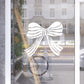 Decorative white bow design on a glass door with a blurred street scene in the background.