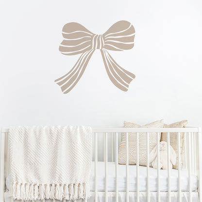 Mushroom coloured bow wall decal above a crib with white bedding and decorative pillows.