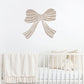 Mushroom coloured bow wall decal above a crib with white bedding and decorative pillows.