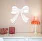 Wall decal of a large white bow on a light pink wall with a small table and lamp in the foreground.