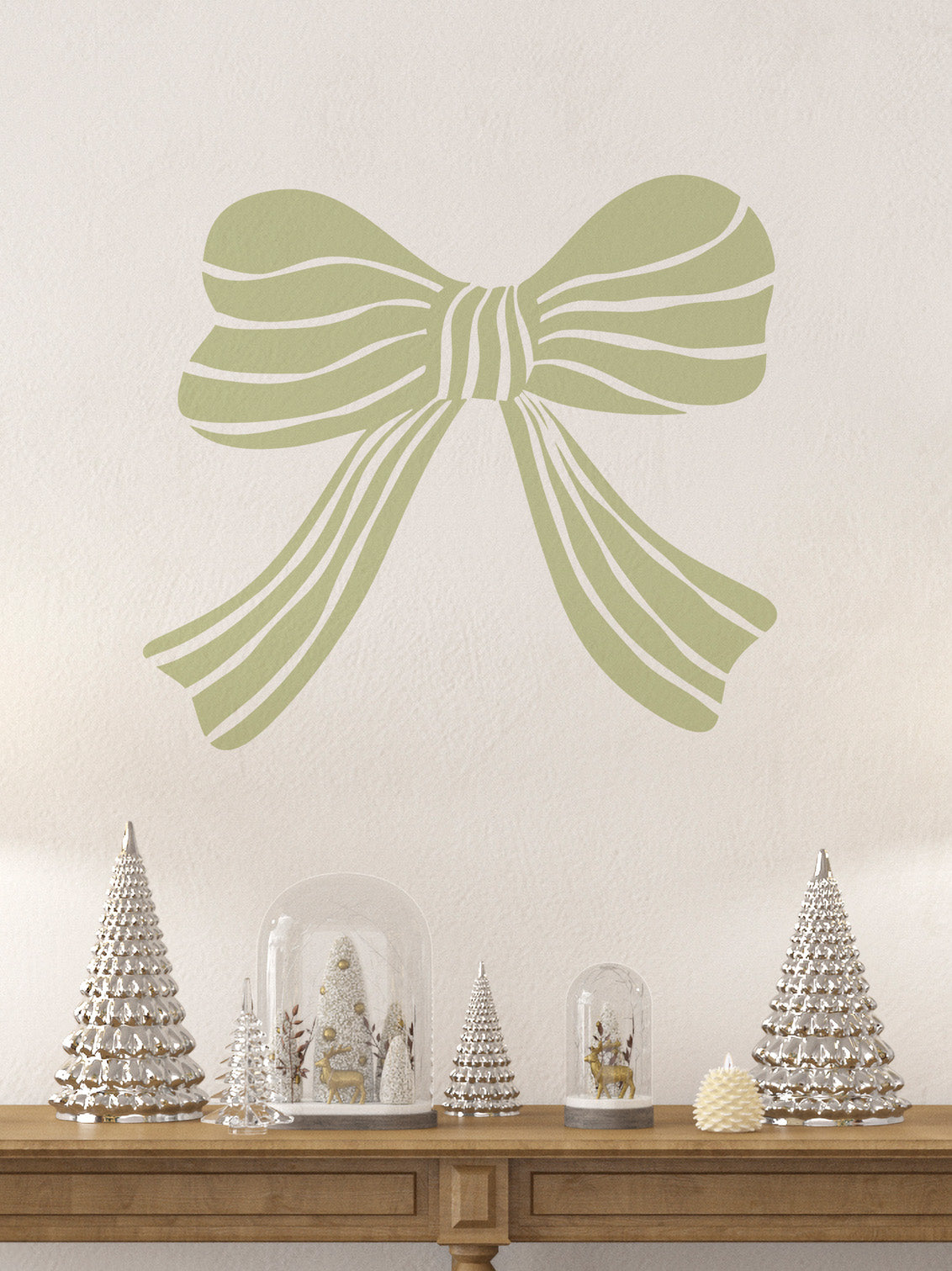 Decorative willow green bow wall decal with Christmas trees and snow globes on a wooden table.