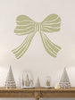 Decorative willow green bow wall decal with Christmas trees and snow globes on a wooden table.