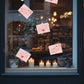 Decorative window display with candles, plants, and Love Letter Retail window sticker heart-themed cards.