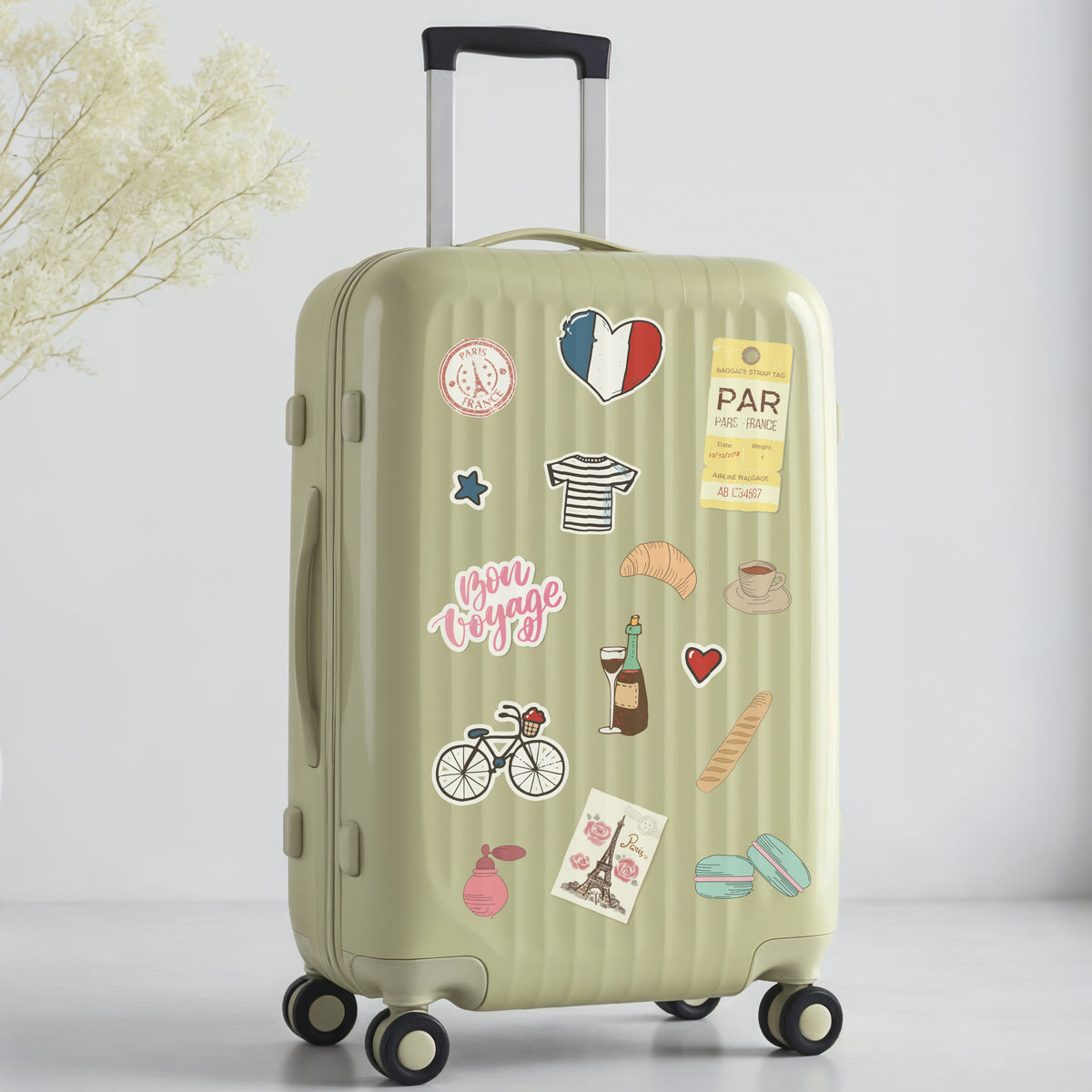 Green suitcase with Paris travel-themed stickers on a light gray background