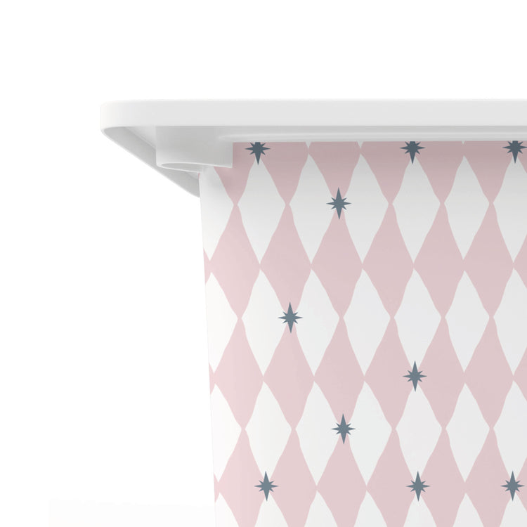 A close-up of a white tub or container edge with a pink and white harlequin diamond pattern wrapped around it, accented with small grey starburst motifs, against a plain white background.