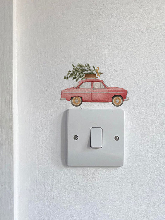 Red Car Carrying a Christmas Tree Light Decoration