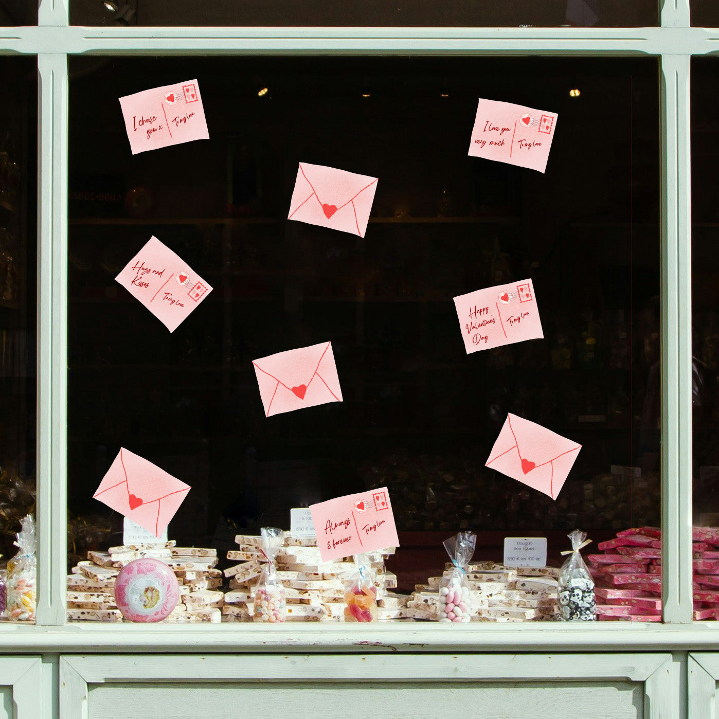 Love letters with heart symbols attached to a window display with baked goods below.
