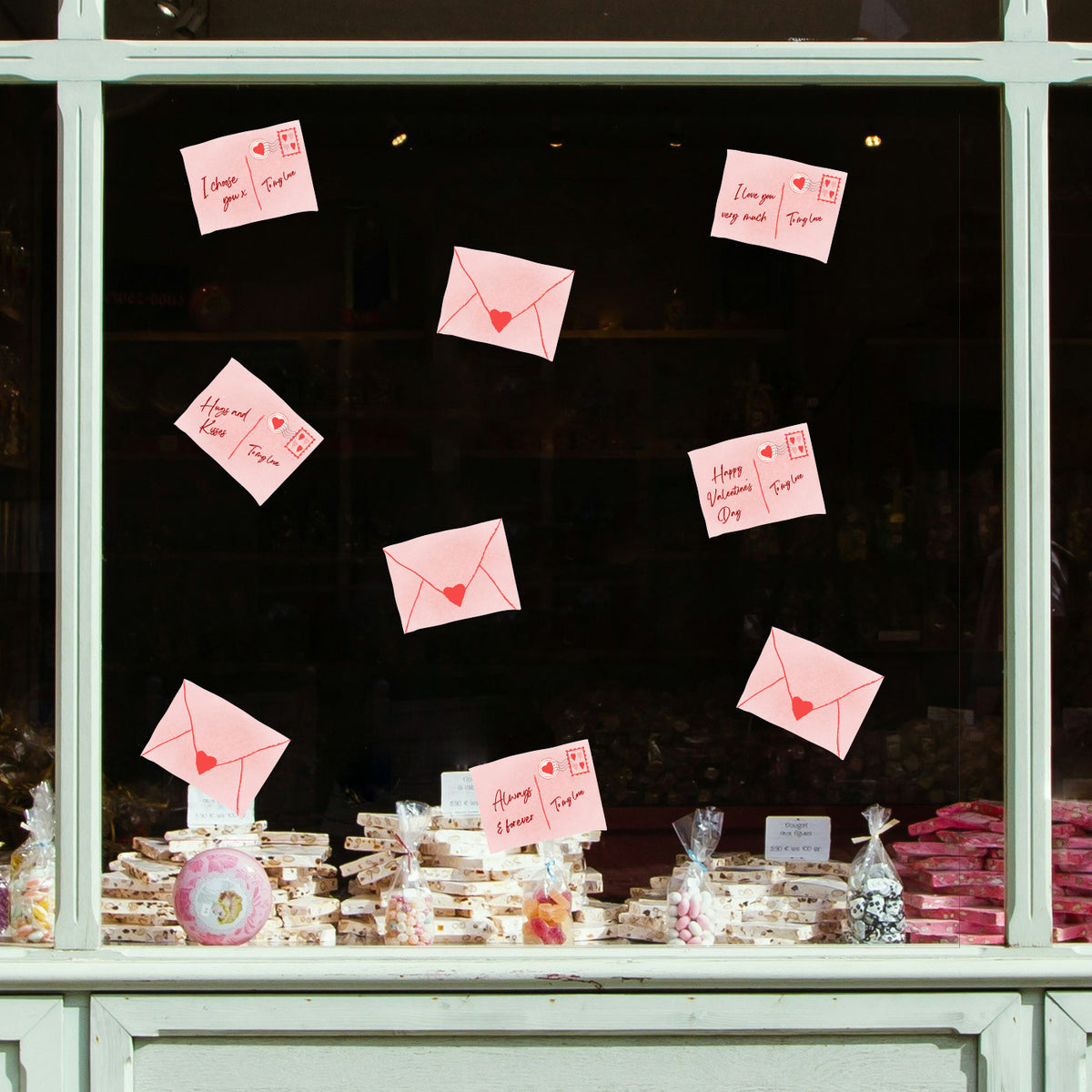Love letters with heart symbols attached to a window display with baked goods below.