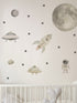 Space-themed wall decals including a rocket, UFOs, and an astronaut on a light gray wall above a crib.