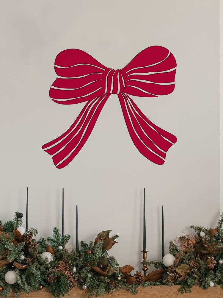 Red bow wall decal above a decorated fireplace with garland and candles.