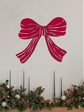 Red bow wall decal above a decorated fireplace with garland and candles.