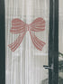 Decorative pink bow on a transparent curtain with a black frame.