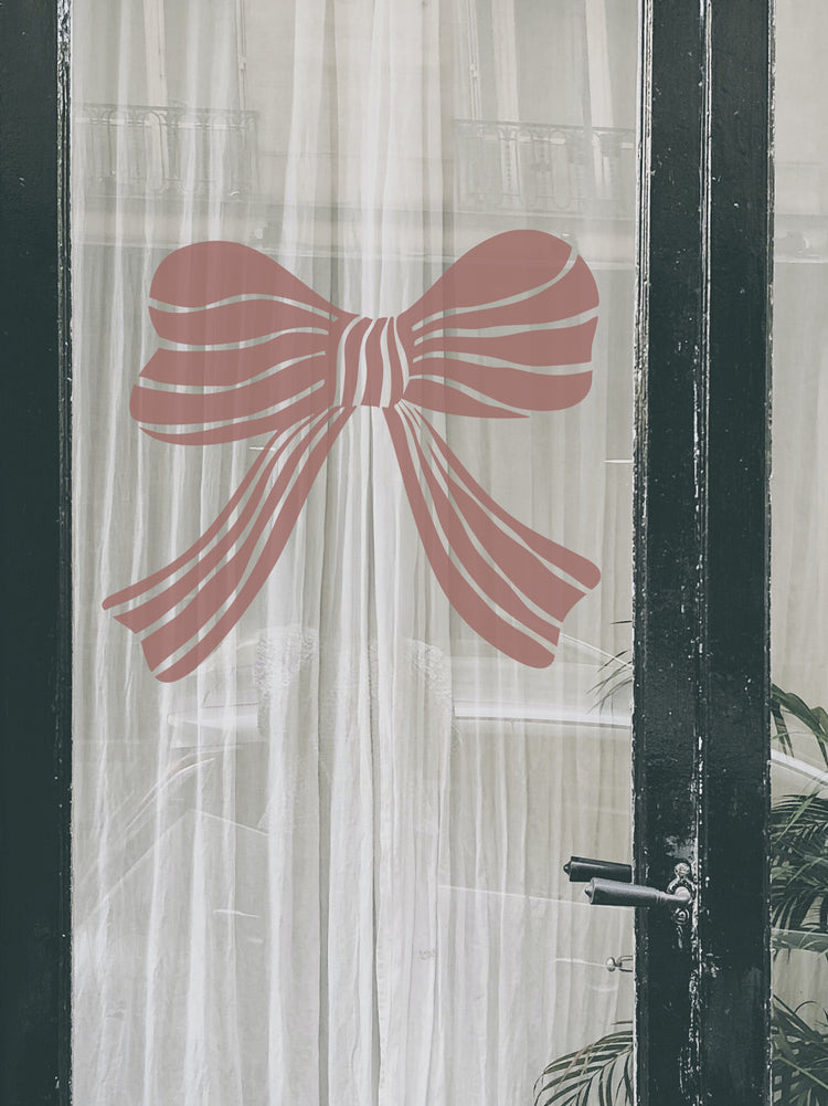 Decorative pink bow on a transparent curtain with a black frame.