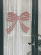 Decorative pink bow on a transparent curtain with a black frame.