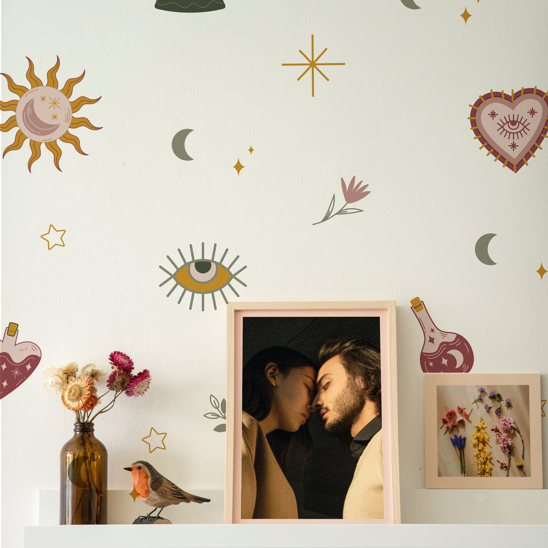 Wall with decorative stickers of a sun, moon, stars, and flowers above a framed photo of a couple.