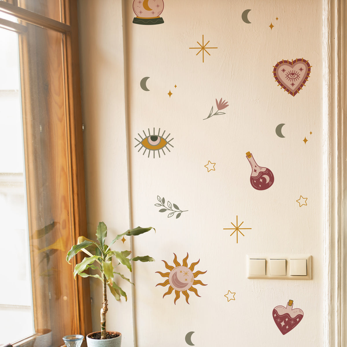 Decorative wall stickers on a light-colored wall with a plant and window in the background.