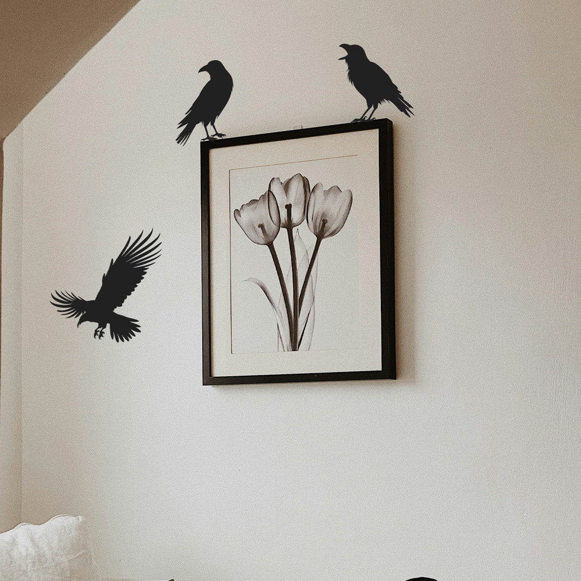 picture frame with two crows standing on each corner at the top and one on the left side flying.