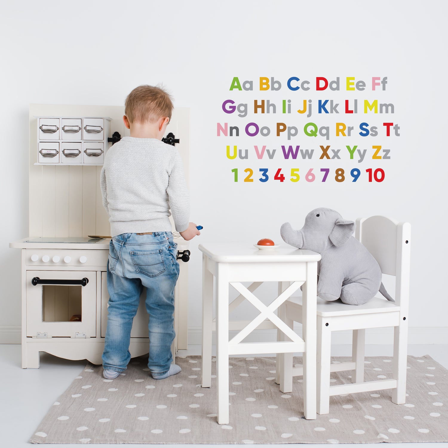 Alphabet & Numbers Wall Sticker. this sticker is the alphabet written out with both upper and lower case letters, with the numbers from 1 to 10 underneath the complete alphabet.All lower case letters in a light grey vinyl, all numbers and  upper case letters in different colours including green, orange, blue, red, yellow, pink, purple and brown.  Shown on a white wall, a children&