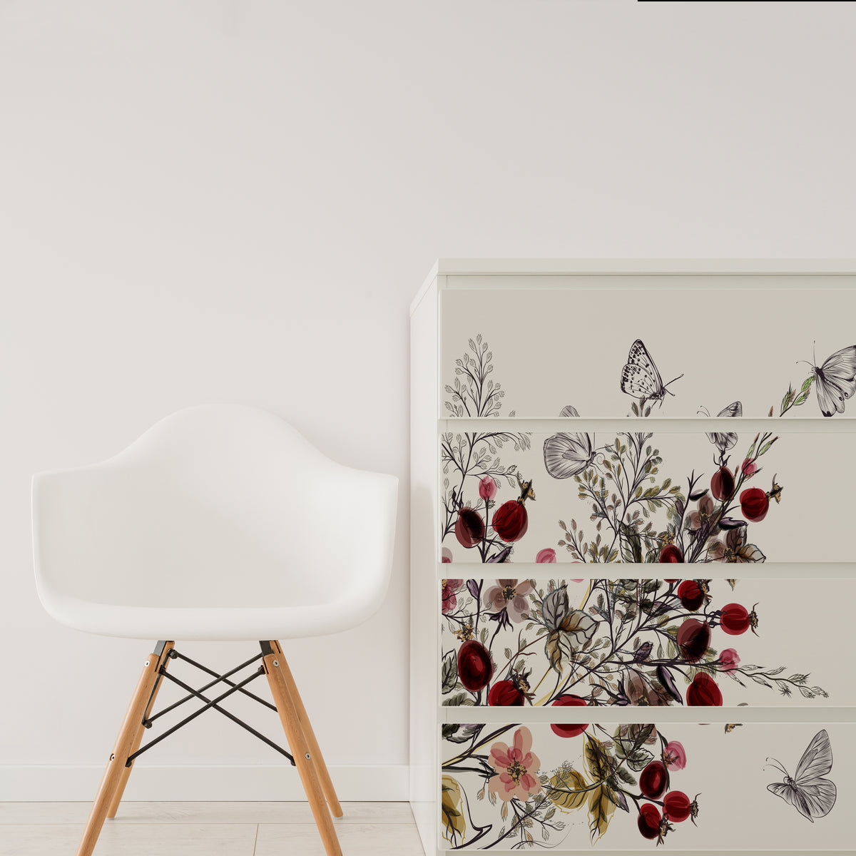 Furniture stickers with a floral and butterfly design applied on an Ikea Malm drawer, in a room with a white chair and a wooden stool beside it.