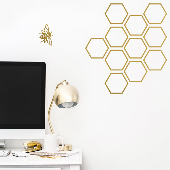 Bee and honeycomb wall sticker in gold on a white wall