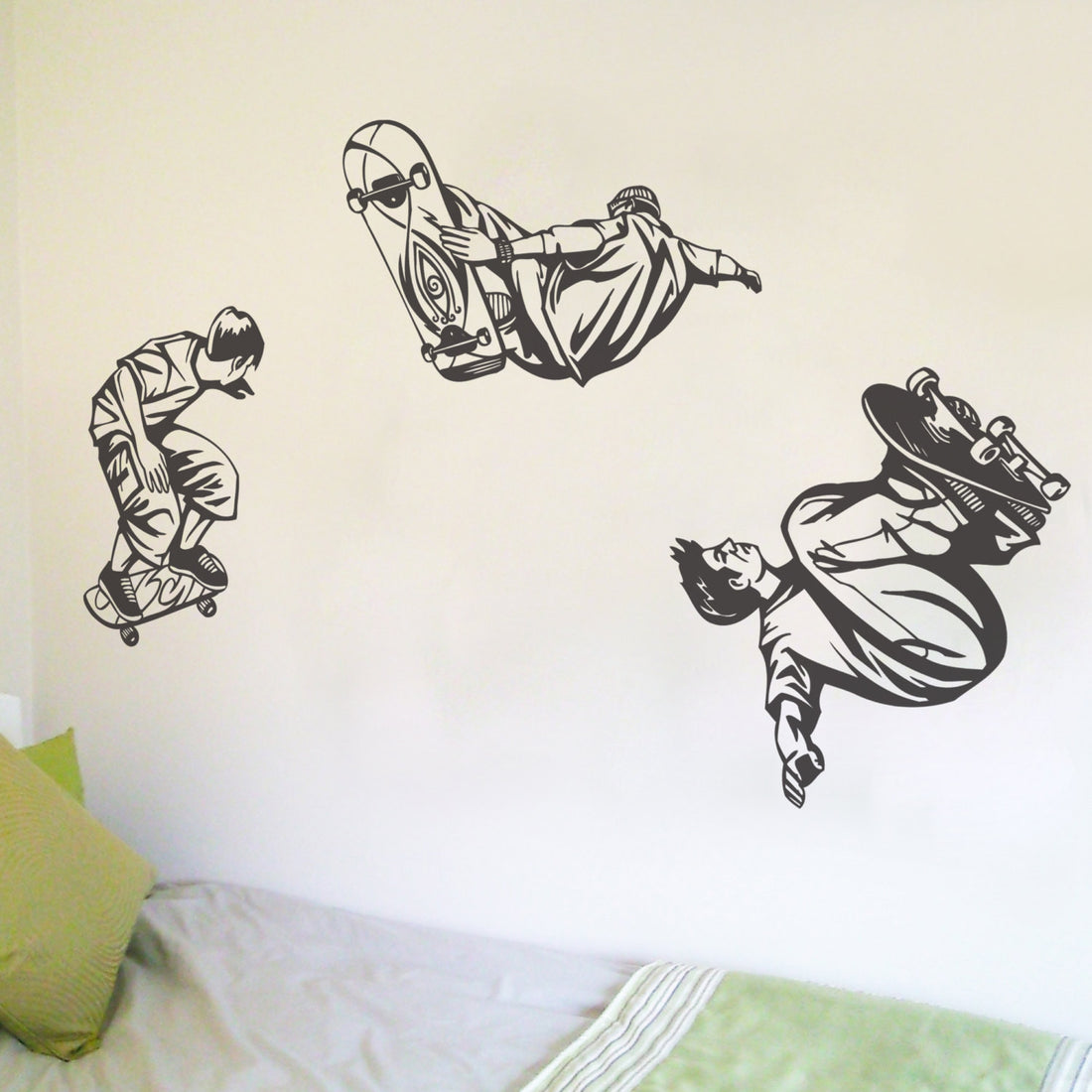 A set of three black and white skateboarder-themed wall stickers applied on a wall, depicting different poses of skateboarders.