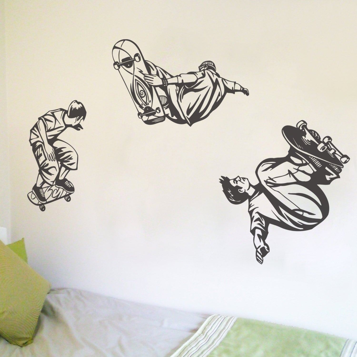A set of three black and white skateboarder-themed wall stickers applied on a wall, depicting different poses of skateboarders.