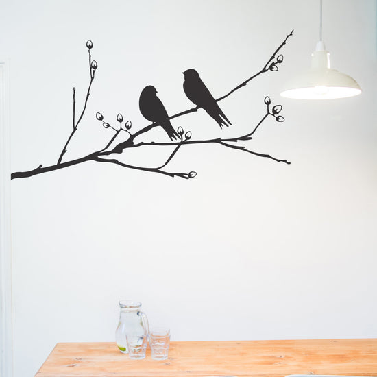 Birds On A Branch Wall Sticker. A perfect piece of decoration when decorating your bedroom or house. Shown in black on a white wall, shows a branch with two birds sitting on it.