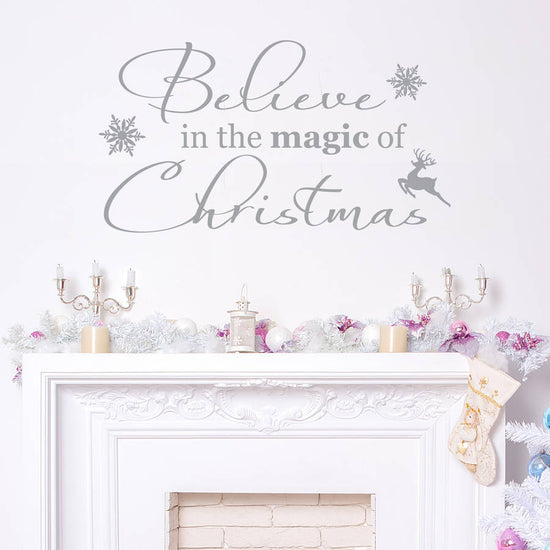 Believe In The Magic Of Christmas Wall Quote. Includes the quote, two snowflakes and a small reindeer sticker. Shown in light grey on a white wall. Perfect for a Christmas decoration for a home.
